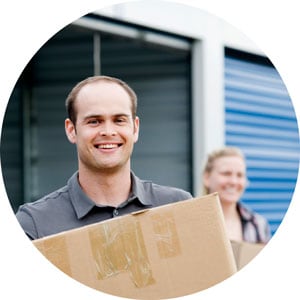 Photo of a smiling man carrying a moving box
